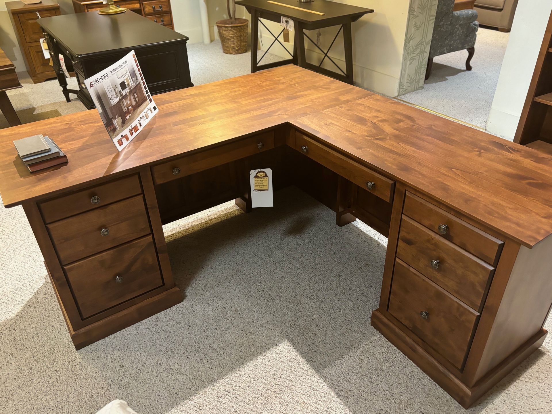L-shaped wooden desk with drawers in a showroom.