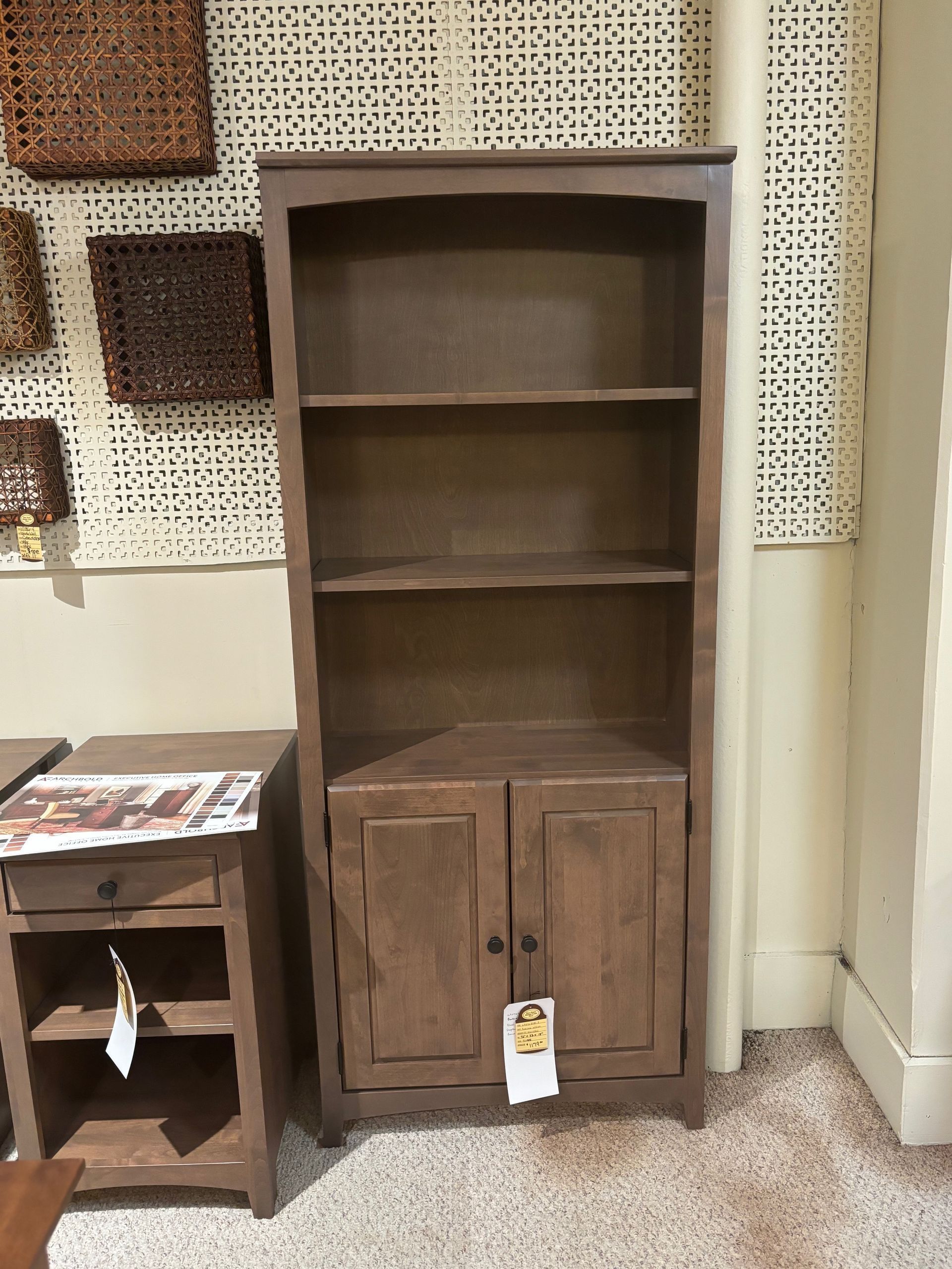 Tall wooden bookshelf with two lower doors, two shelves, and a dark brown finish.