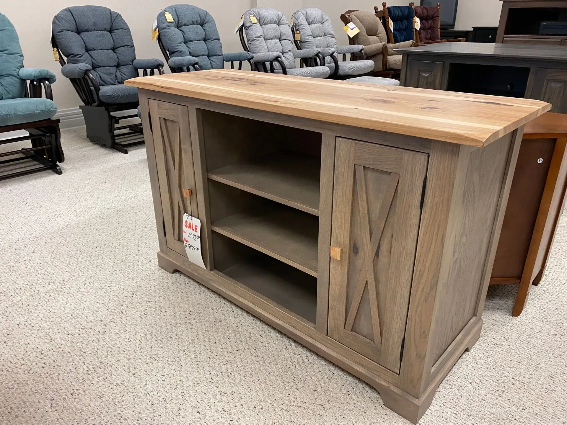 Wooden entertainment center with open shelves and barn-style doors; light brown finish.