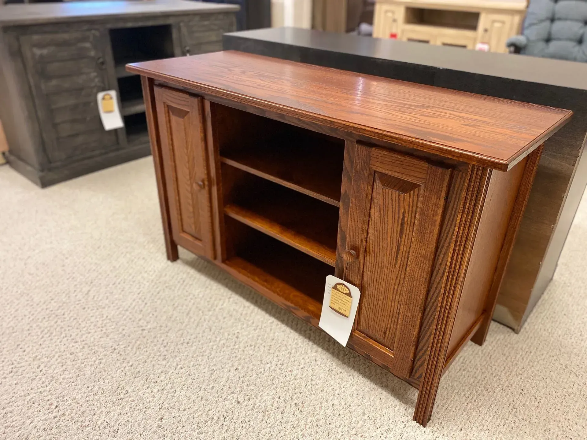Wooden TV console cabinet with two doors and open shelves, displayed in a store.