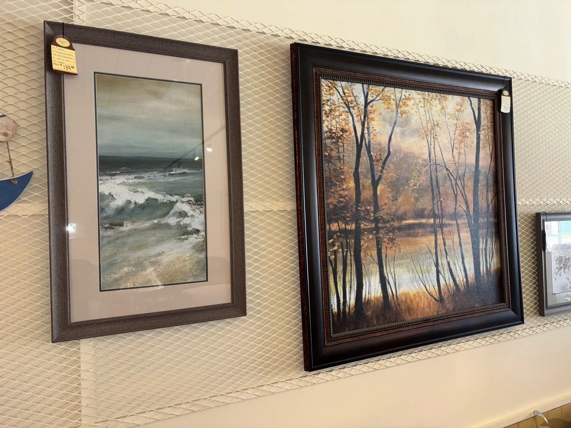 Two framed landscape paintings on a textured beige wall.