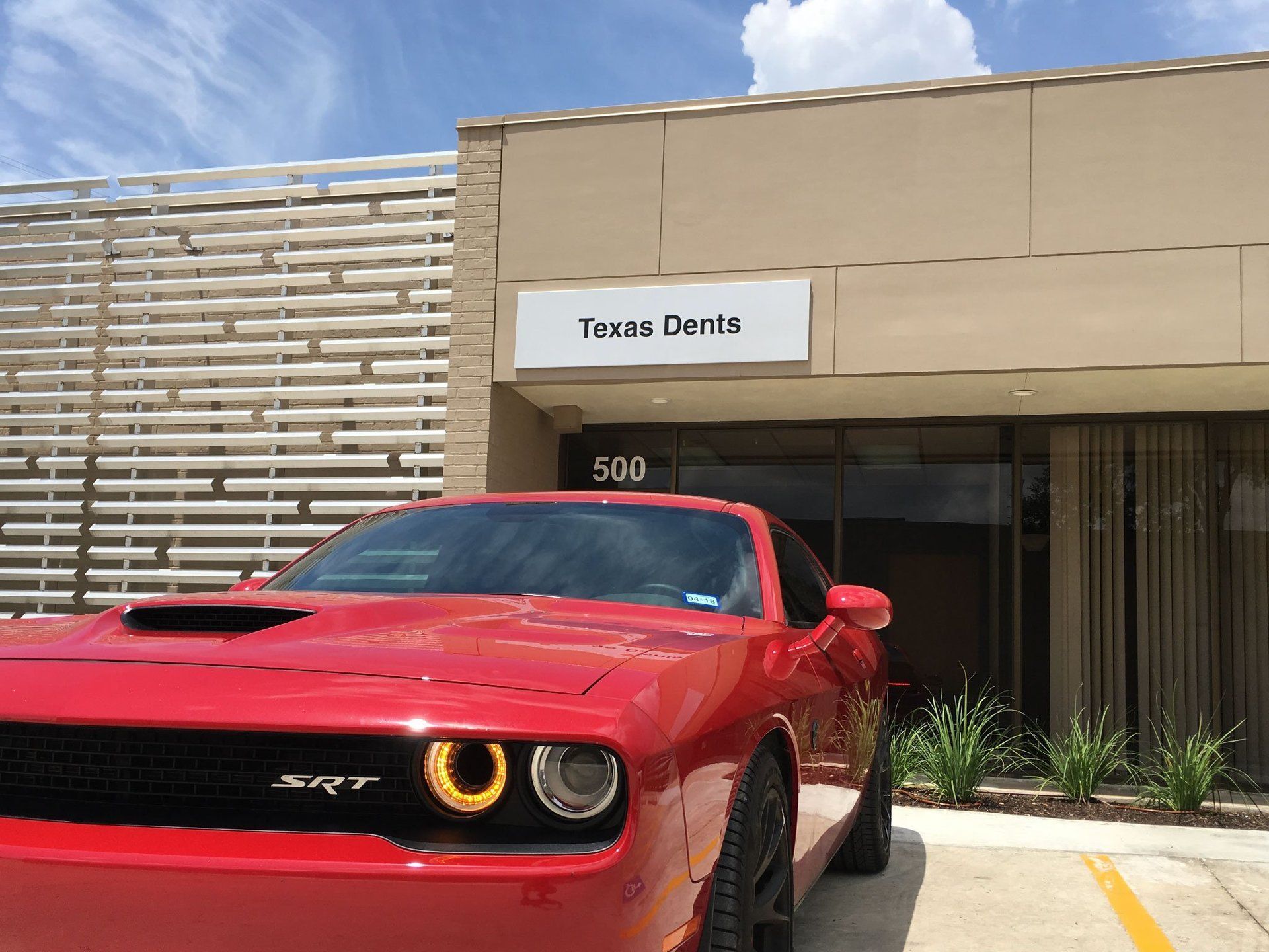 a red car is parked in front of a building that says texas dents