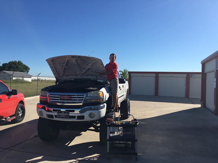 a man is standing next to a truck with the hood up .