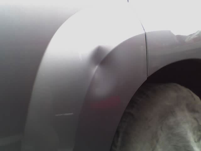 a close up of a car 's fender with a dent in it .