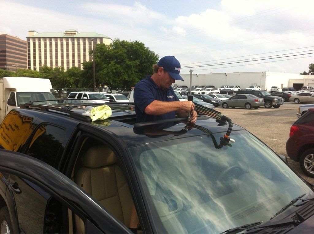 a man is working on a car windshield in a parking lot