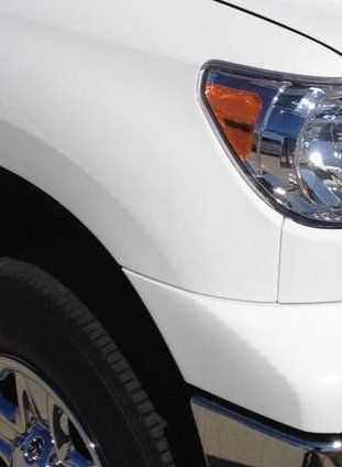a close up of a white truck 's headlight and tire
