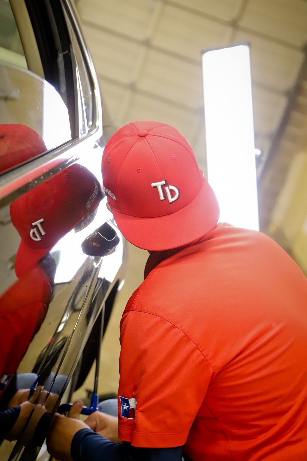 a man wearing a red hat that says td is working on a car