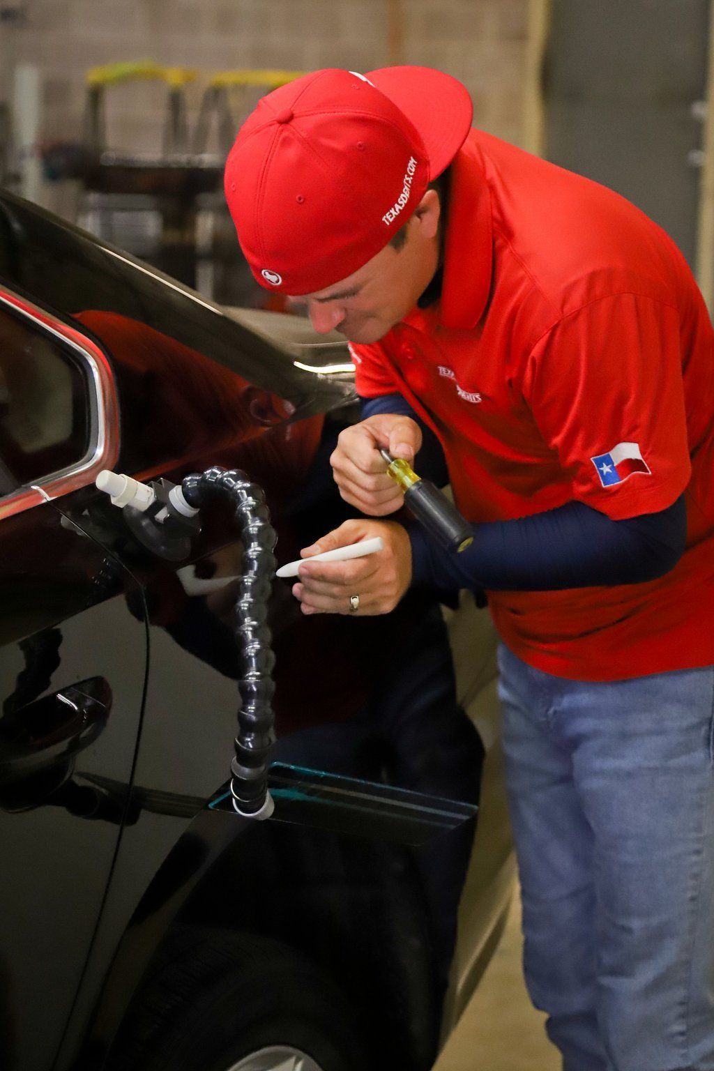 a man in a red shirt is working on a car