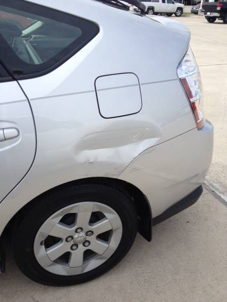a silver car with a damaged side is parked in a parking lot