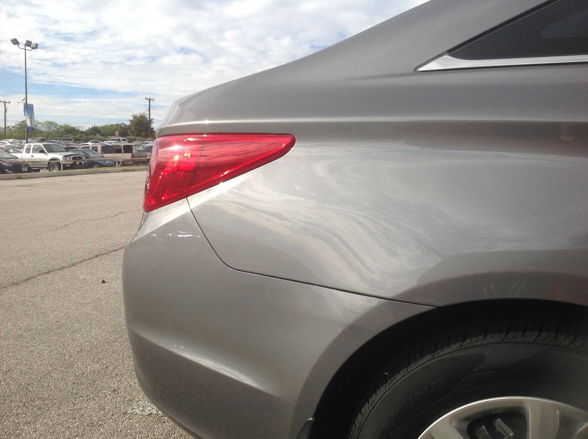 a silver car with a red tail light is parked in a parking lot