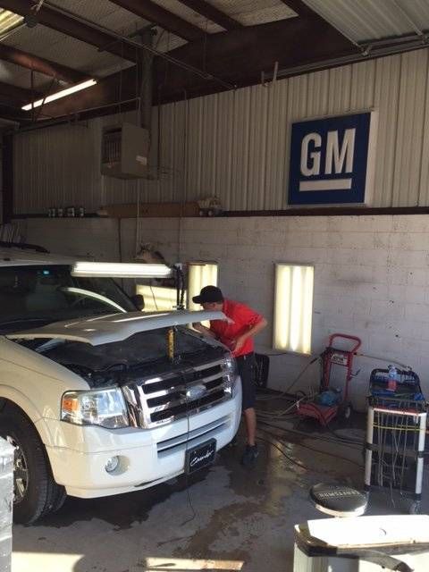 a gm sign hangs above a car in a garage