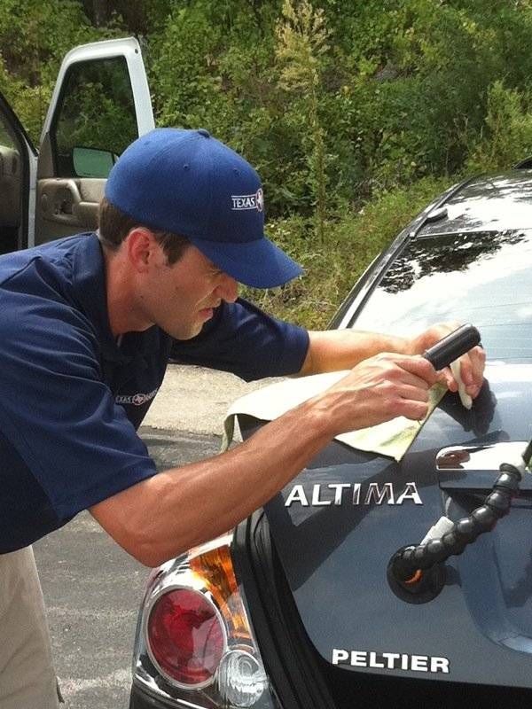 a man in a blue hat is working on a black altima