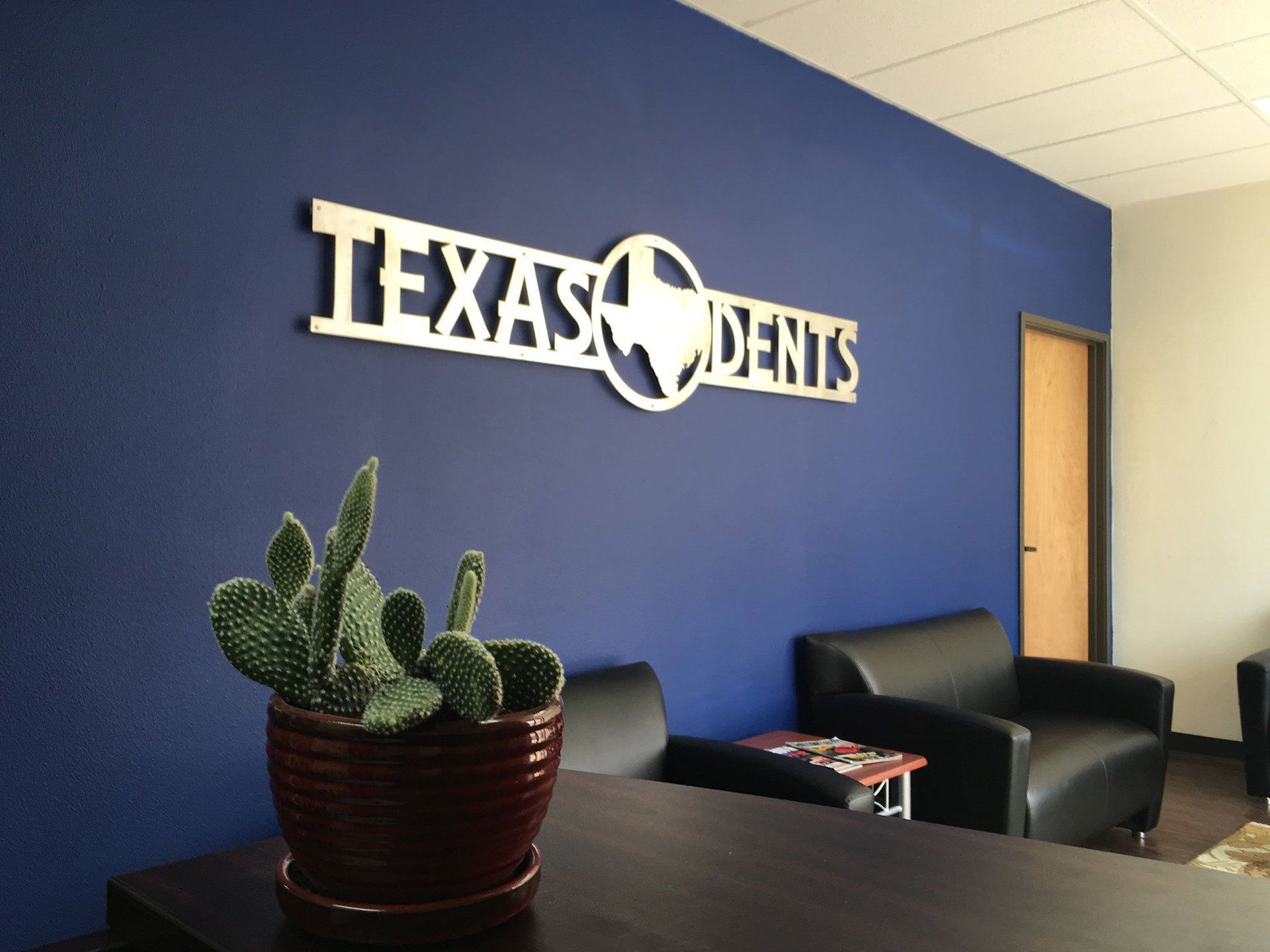 a cactus sits in front of a sign that says texas dents