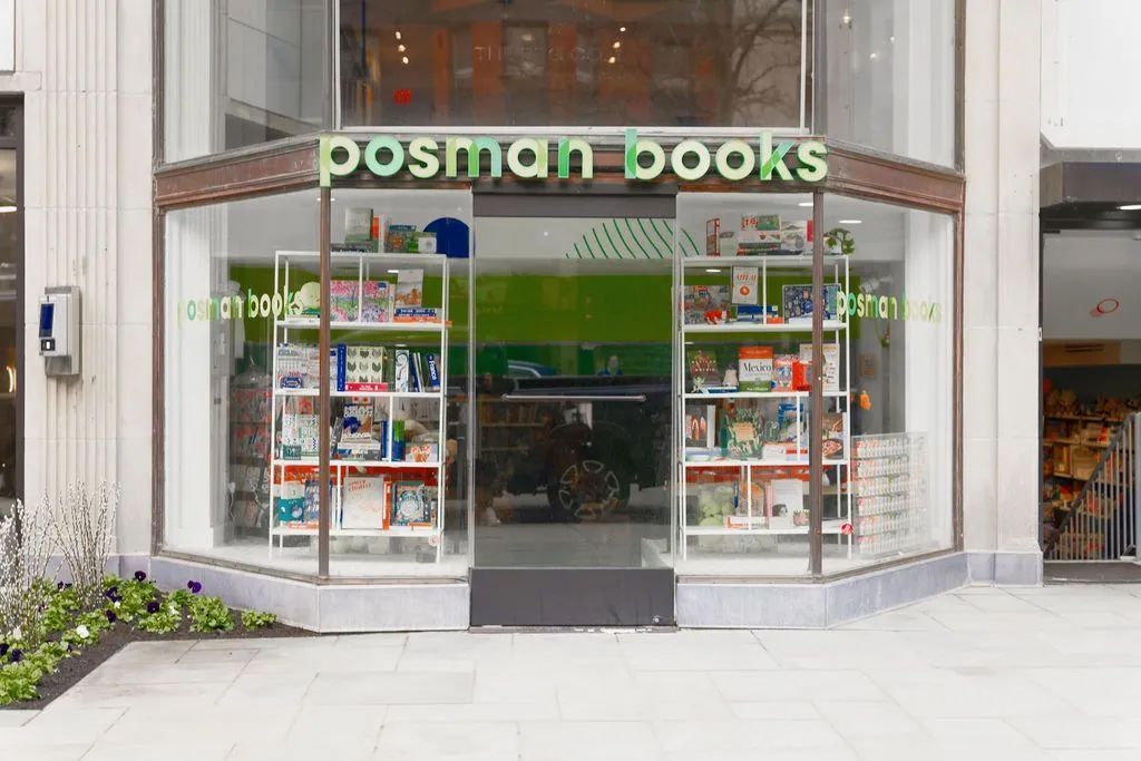 Front entrance of Postman Books storefront with glass windows and green signage.