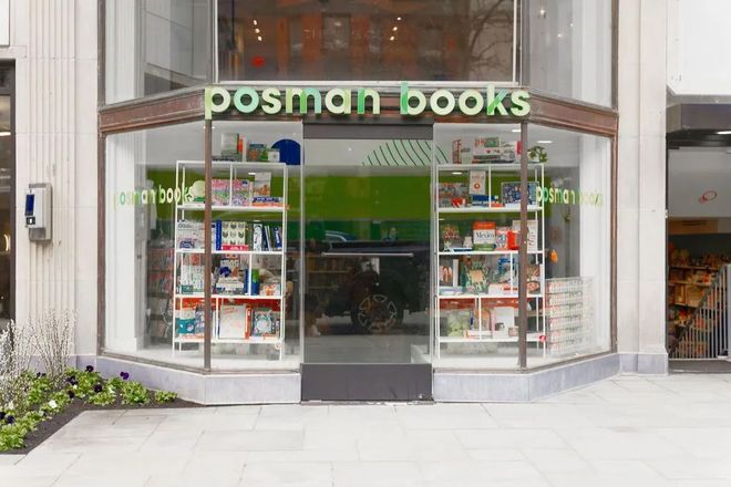Front entrance of Postman Books storefront with glass windows and green signage.