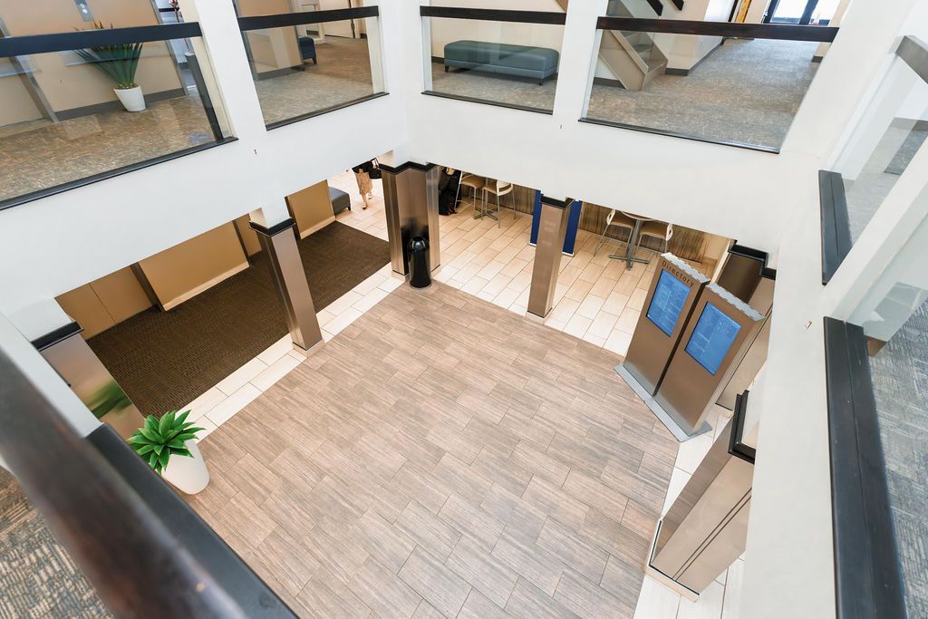 Empty indoor atrium with tiled floor, glass railings, and cardboard boxes along the walls