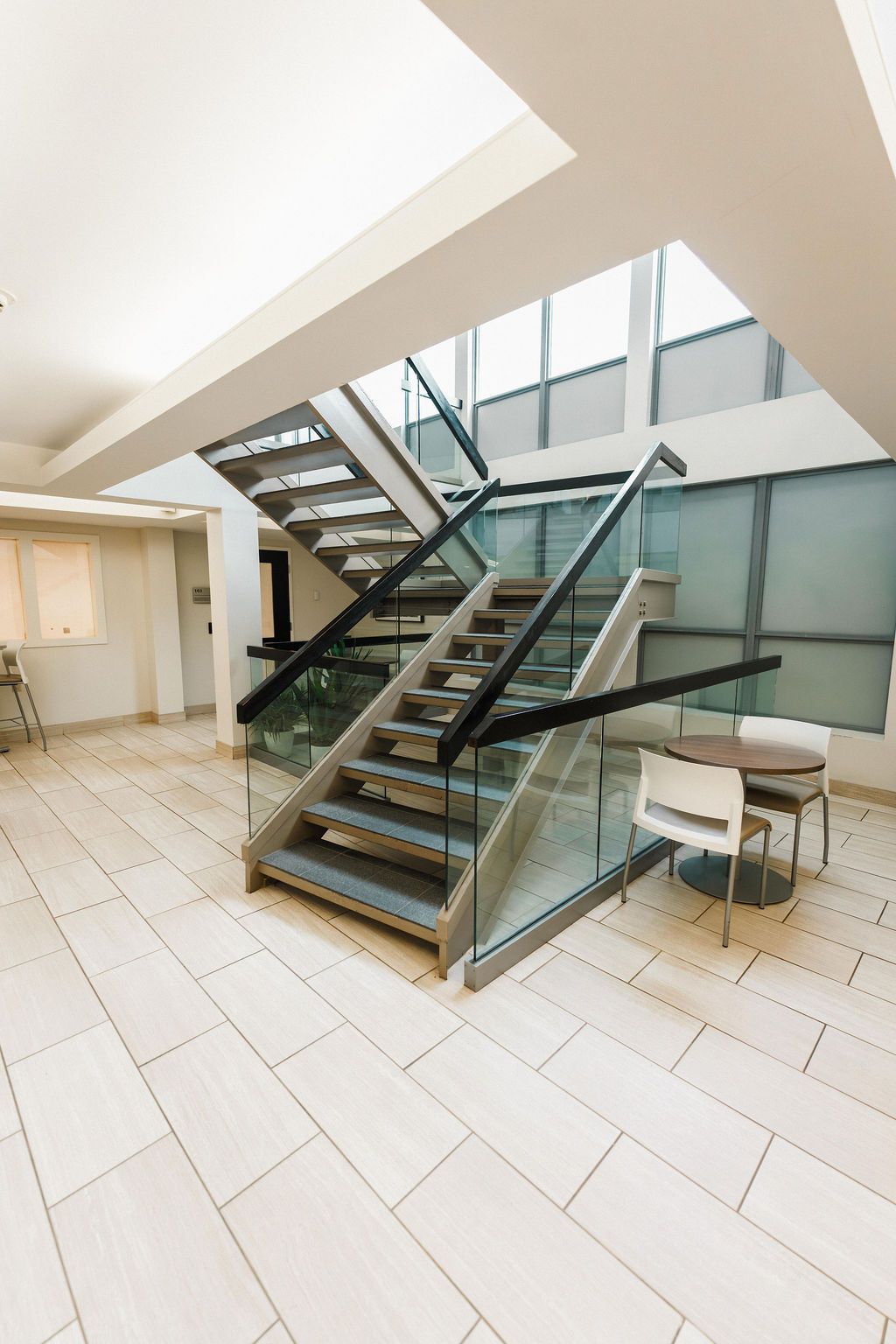 Modern stairway with glass railings in a bright tiled lobby