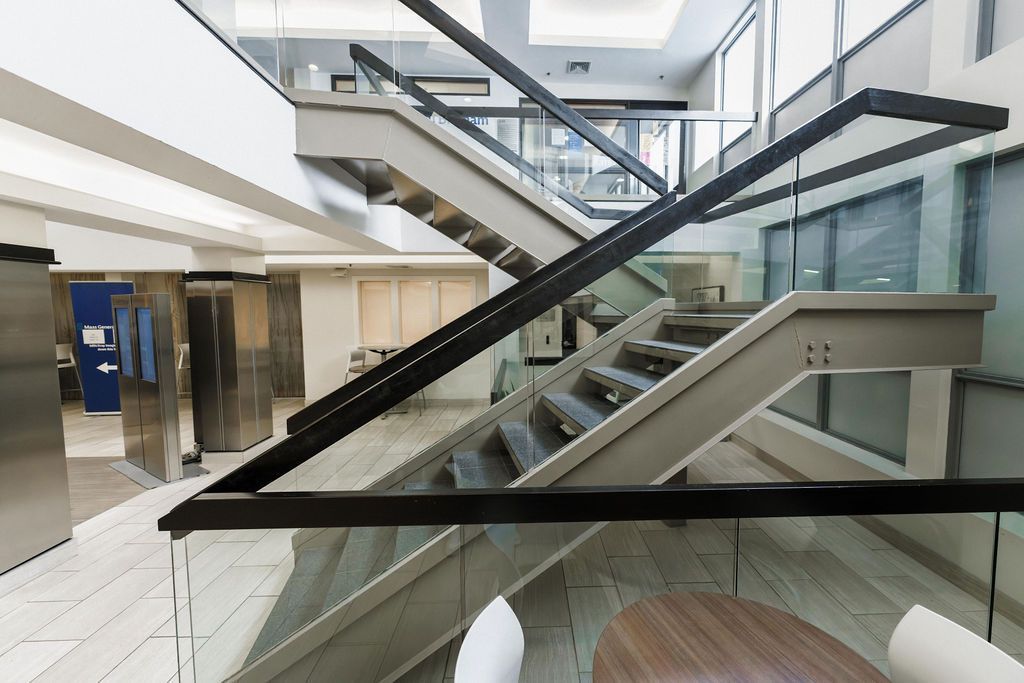 Modern indoor atrium with glass railings and intersecting staircases in a bright office or mall space