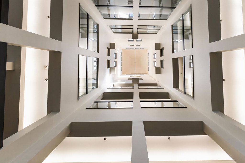 Modern atrium with white beams, glass walls, and a symmetrical view looking upward