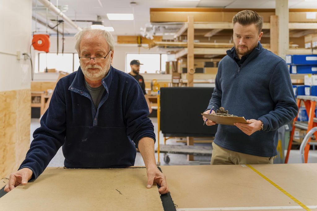 Two men inspecting a large wooden board in a workshop