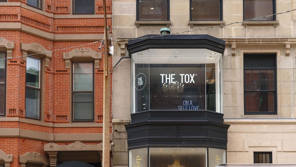 Storefront with a black sign reading 'THE TOX' between red brick and beige buildings