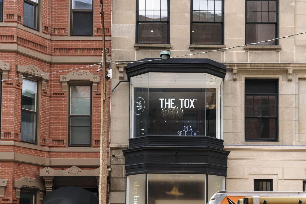 Storefront with black sign reading 'THE TOX' on a brick and stone building facade.