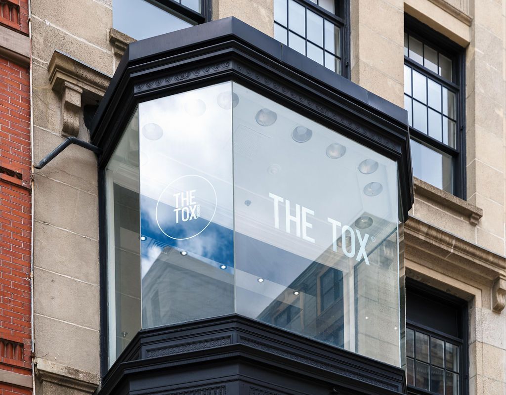 Glass storefront sign reading 'THE TOY' on a black corner building facade