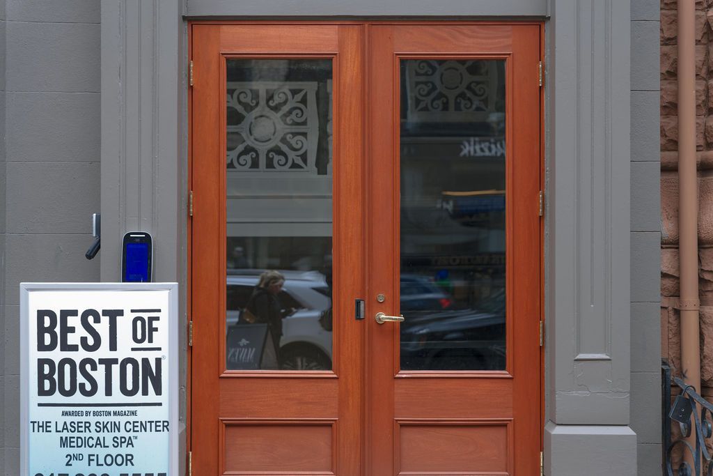 Orange double doors with glass panes and a 'Best of Boston' sign outside a building