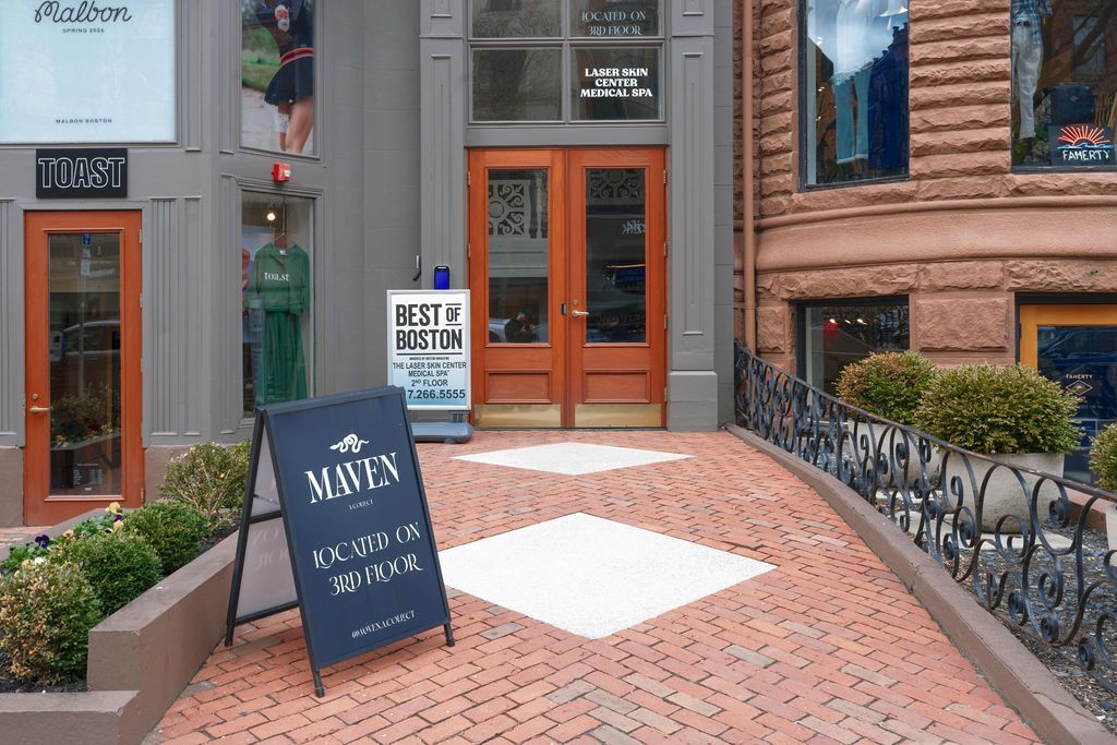 Storefront entrance with orange doors, brick walkway, and a sidewalk sign outside a café or shop