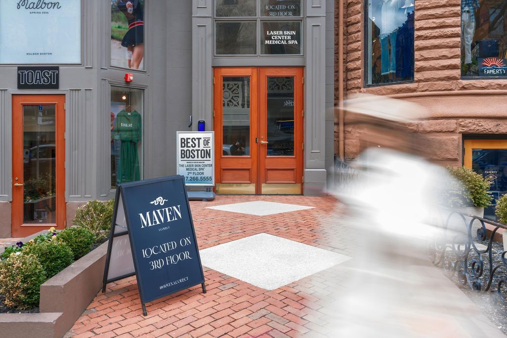 Storefront with orange doors, brick walkway, and sandwich board signs outside a café