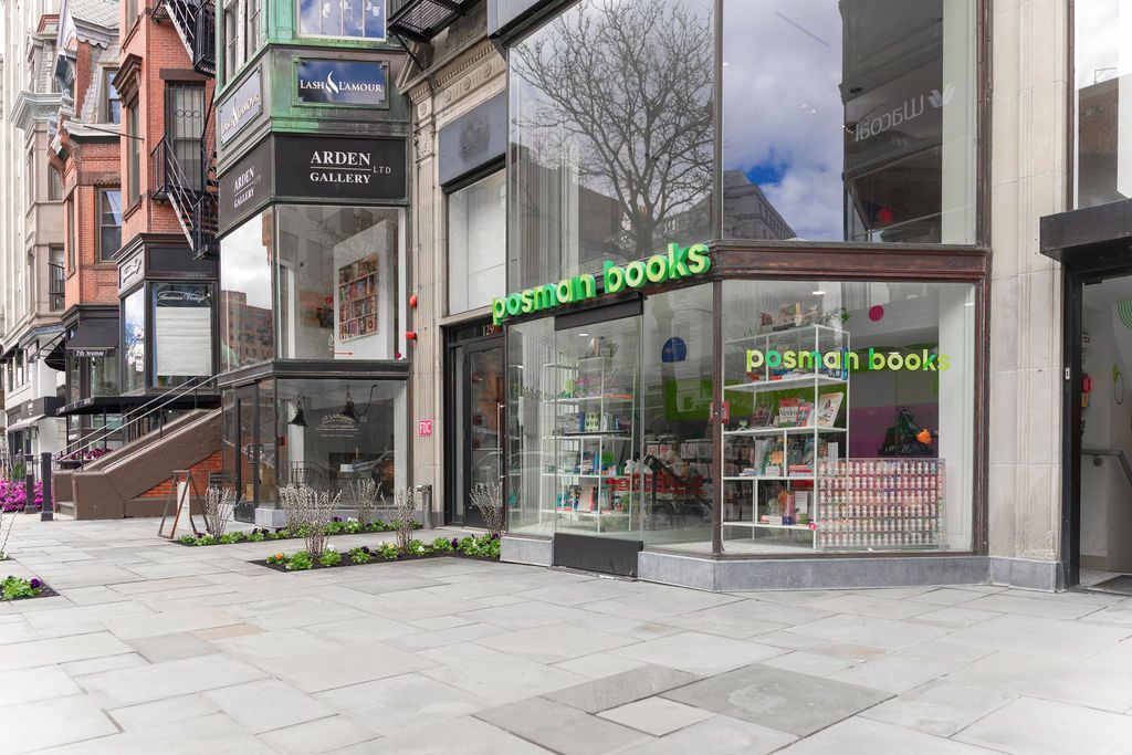 Street-level view of a bookstore with green signage and large glass windows on a city sidewalk.