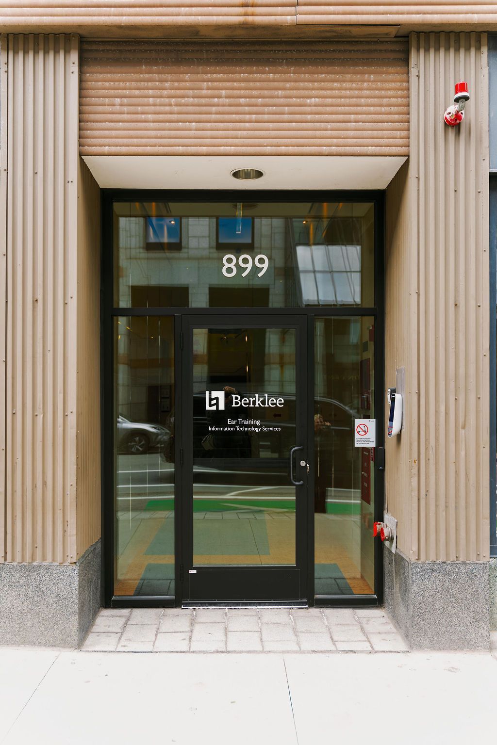 Glass storefront entrance with number 899 and green-trimmed doors on a city sidewalk