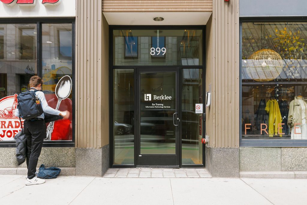 Storefront entrance with glass doors and the number 899 above the doorway; a person walks past on the left.