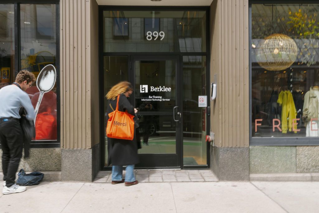 Two people enter a storefront with number 899 above the glass door.