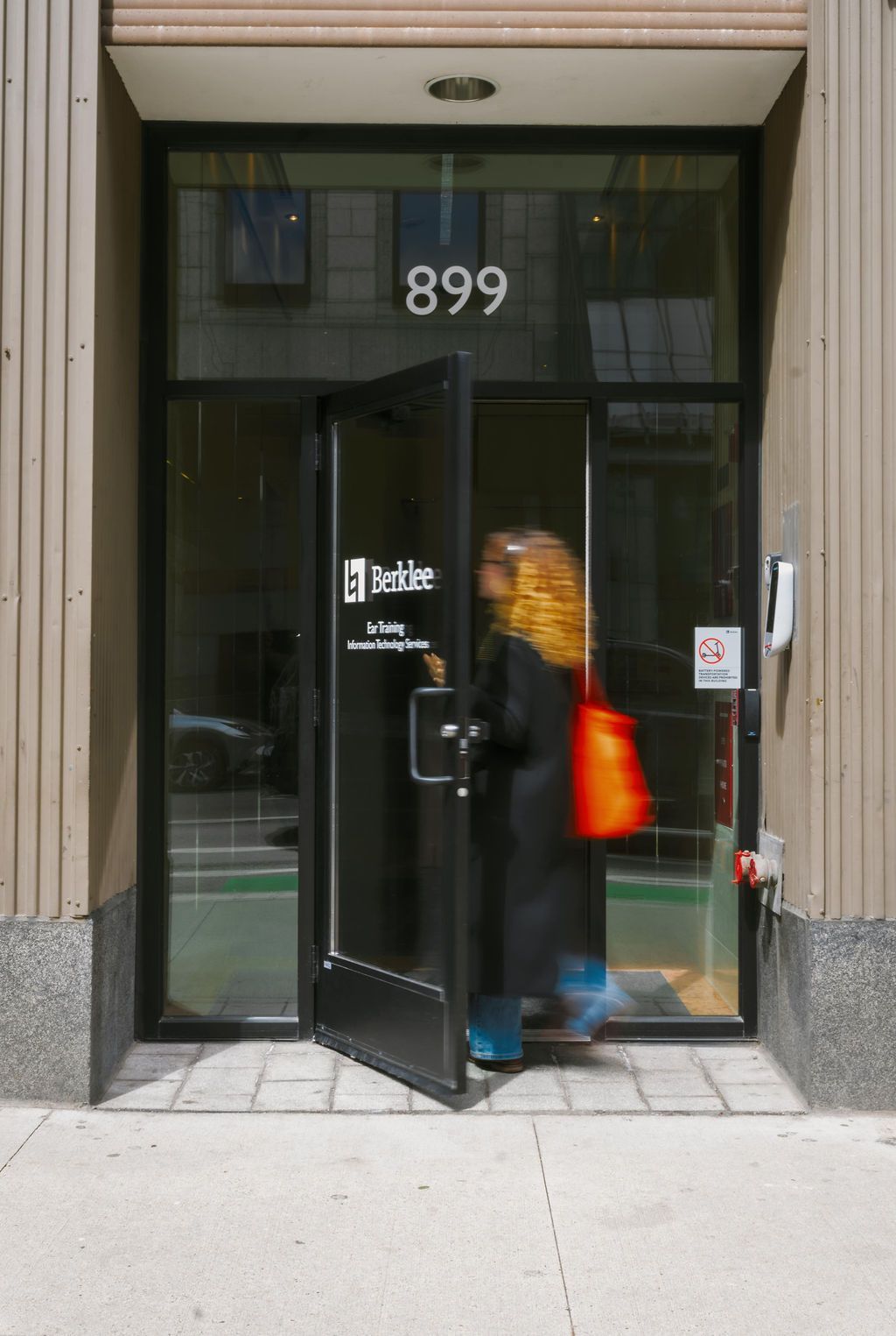 Person entering glass storefront doorway with number 899 above it