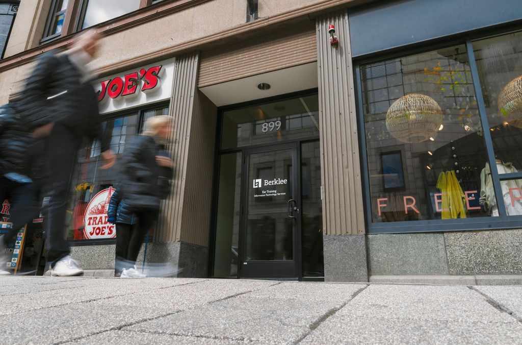 People walking past a storefront with a black door and large window display