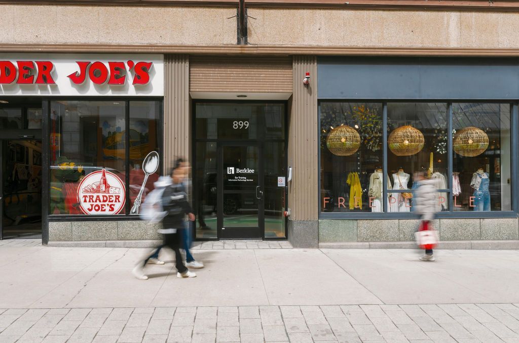 Storefront with two blurred pedestrians walking past display windows on a city sidewalk