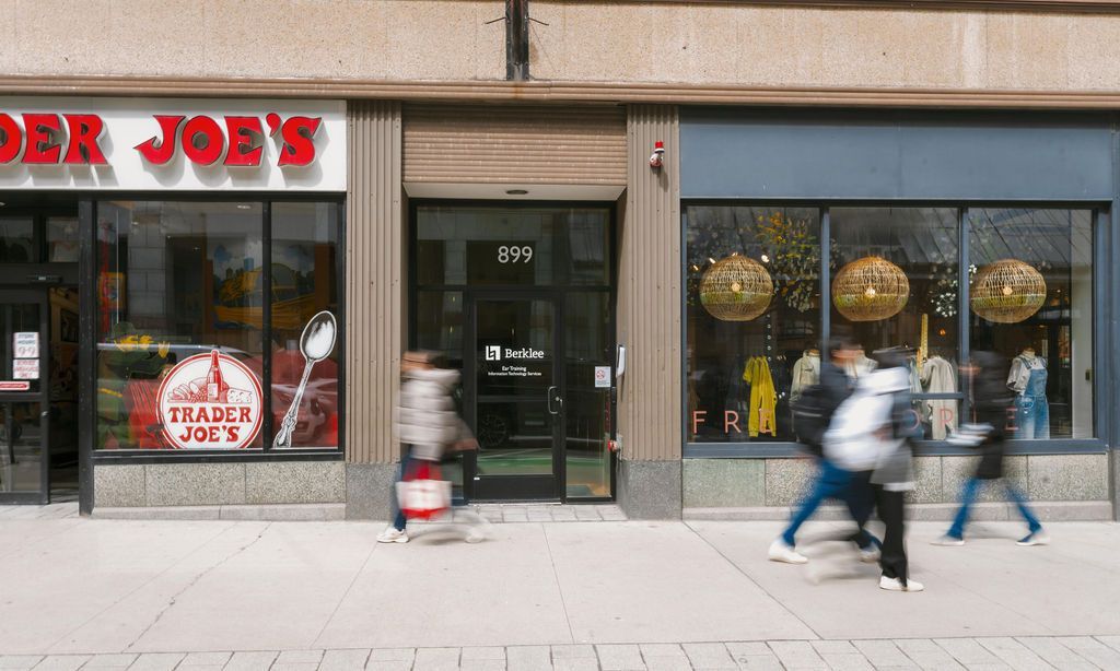 Storefront with people walking past and a blurred runner on the sidewalk; red 'JOE’S' sign visible.