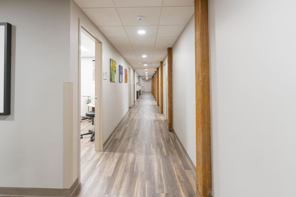 Long office hallway with white walls, wood trim, and light wood floors