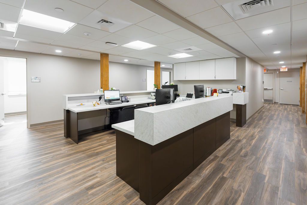 Modern office reception area with long white front desk, dark wood base, and carpeted flooring