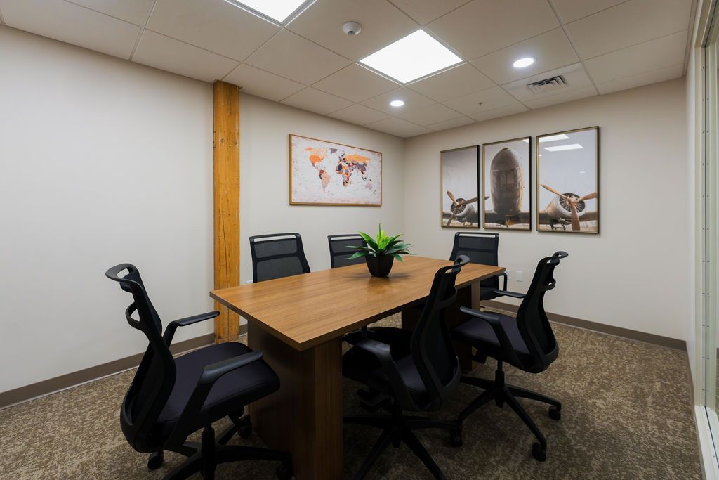 Modern conference room with wooden table, black office chairs, and framed wall art.
