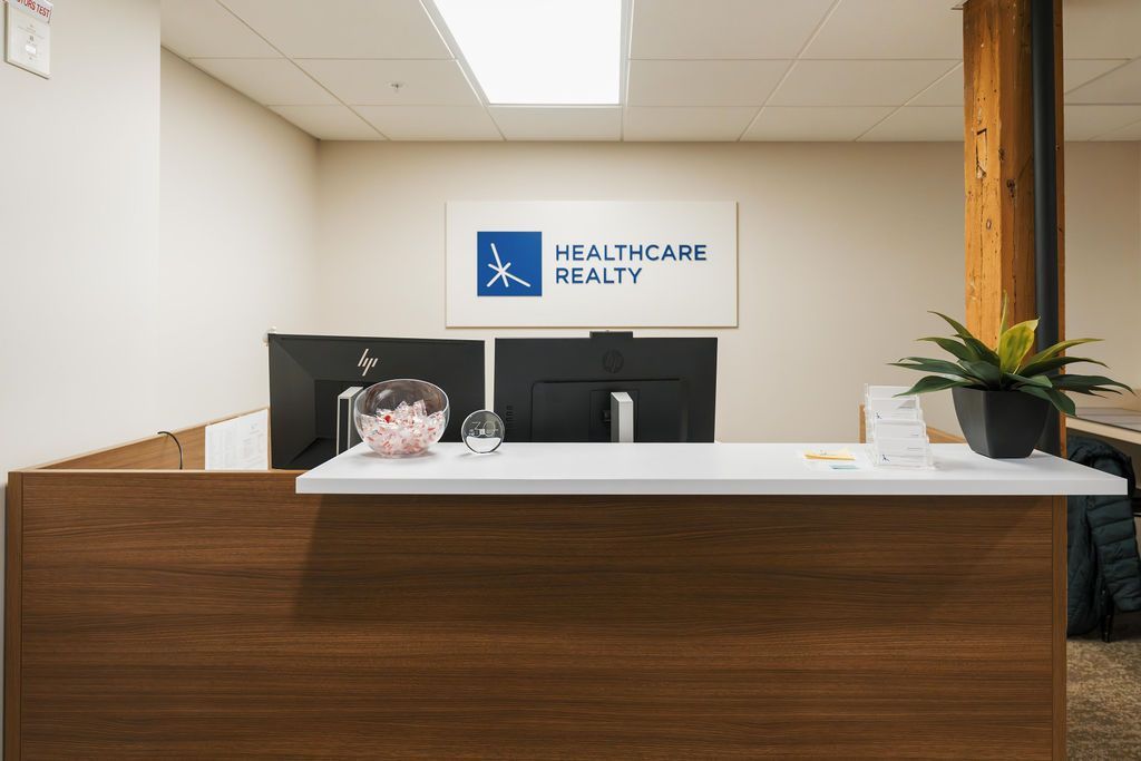 Modern dental reception desk with white counter, wood paneling, and clinic sign on the wall