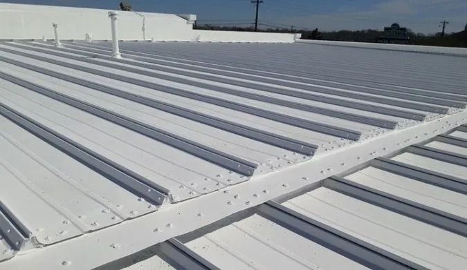 A white, ribbed metal roof with a horizontal seam across the middle, showing a commercial building exterior.