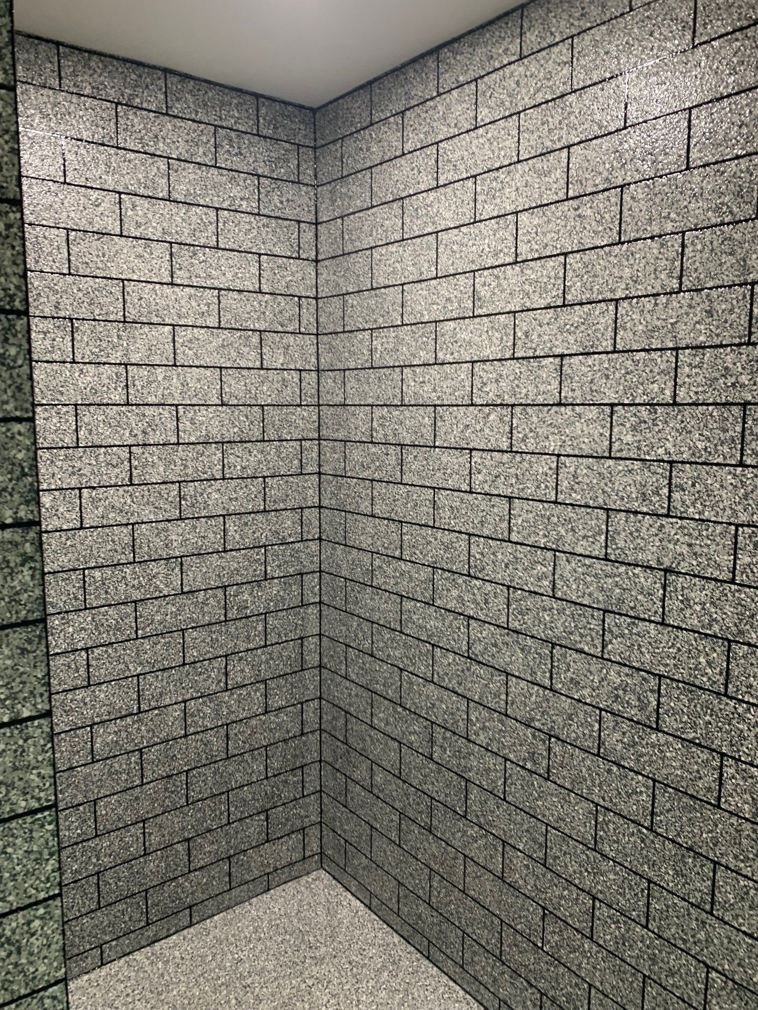 Empty gray cinderblock room corner with a white ceiling and floor.