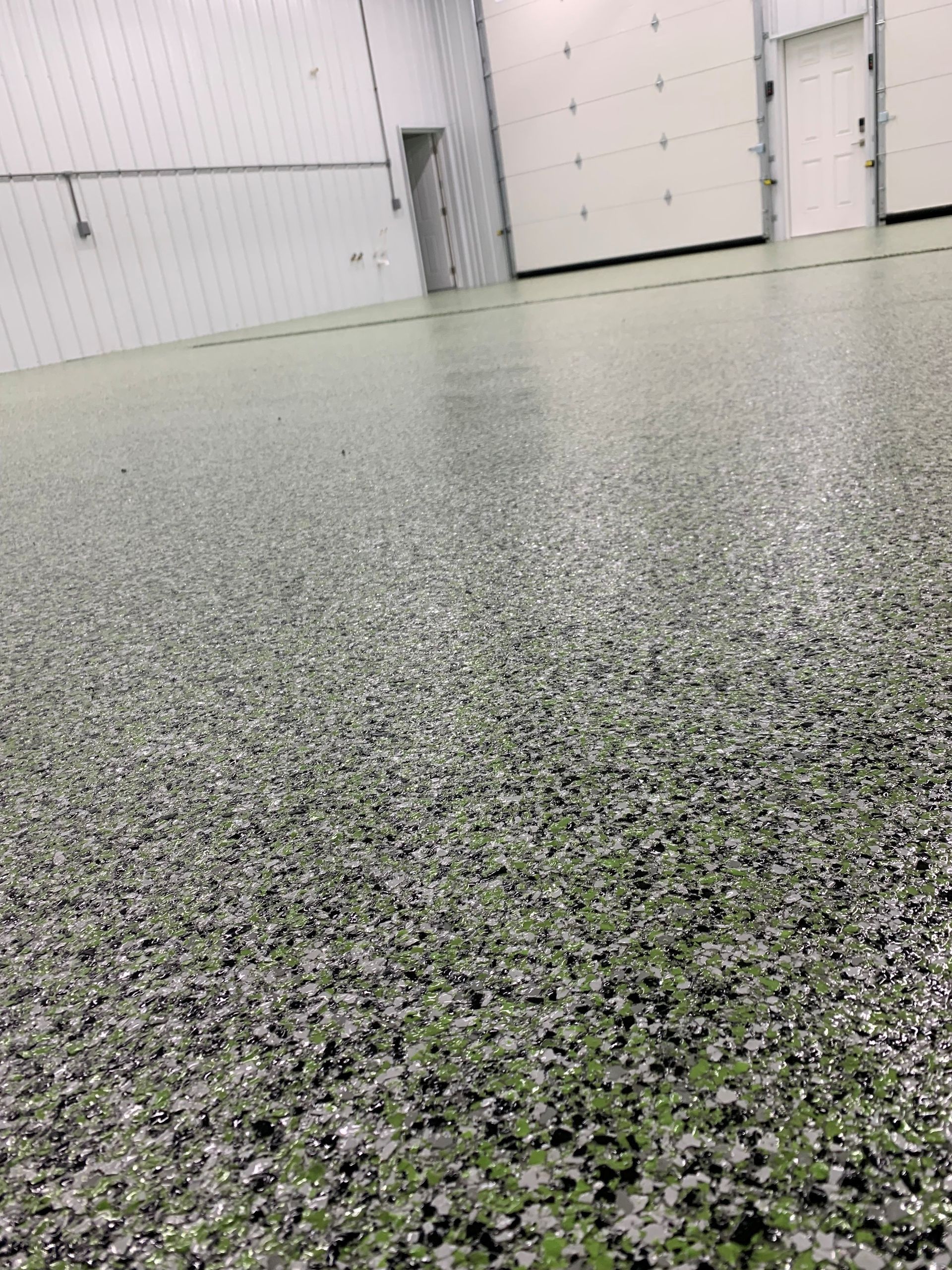 Speckled epoxy floor in a clean garage with white walls and closed doors