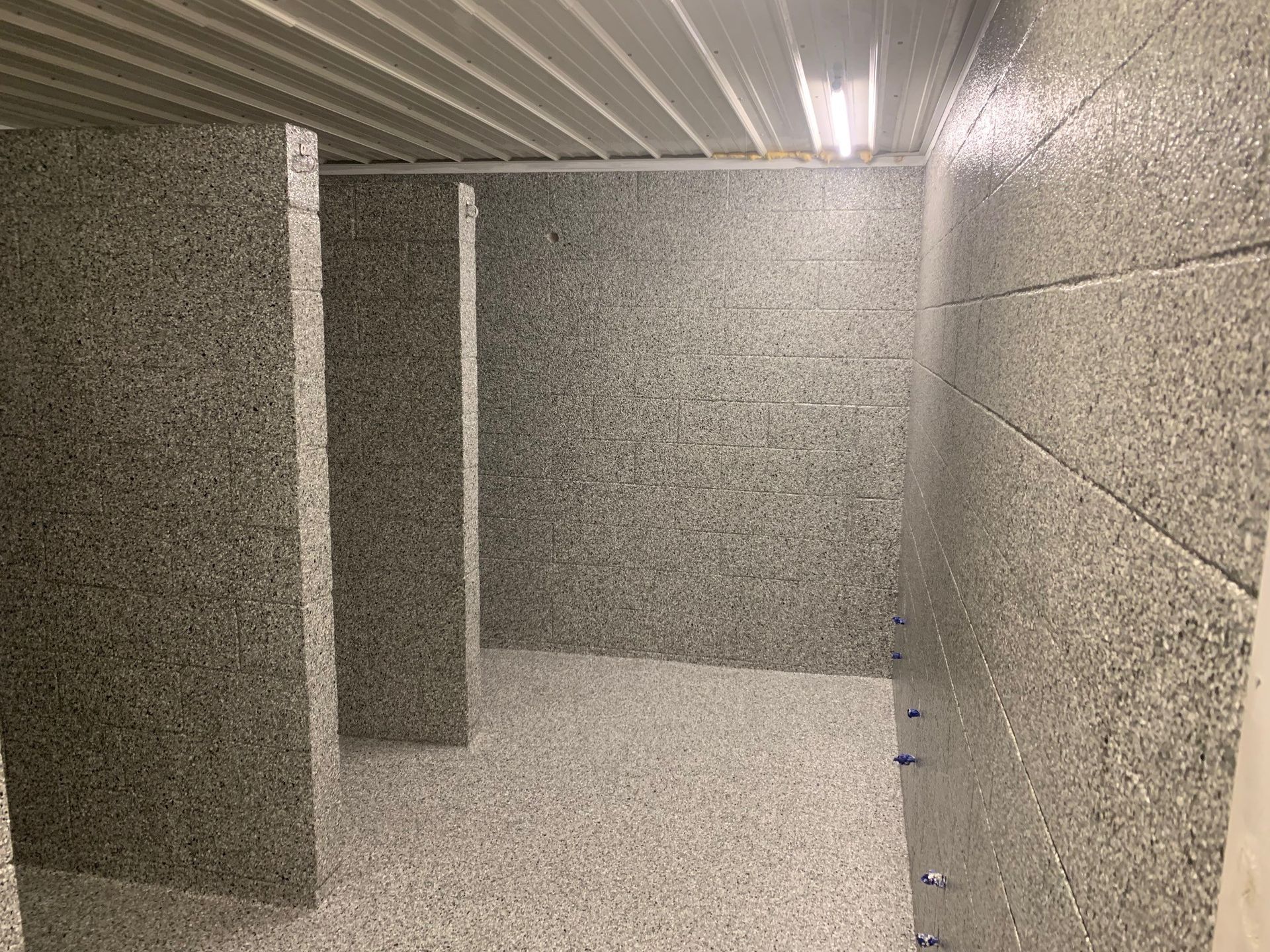 Empty concrete hallway with gray walls and fluorescent ceiling lights