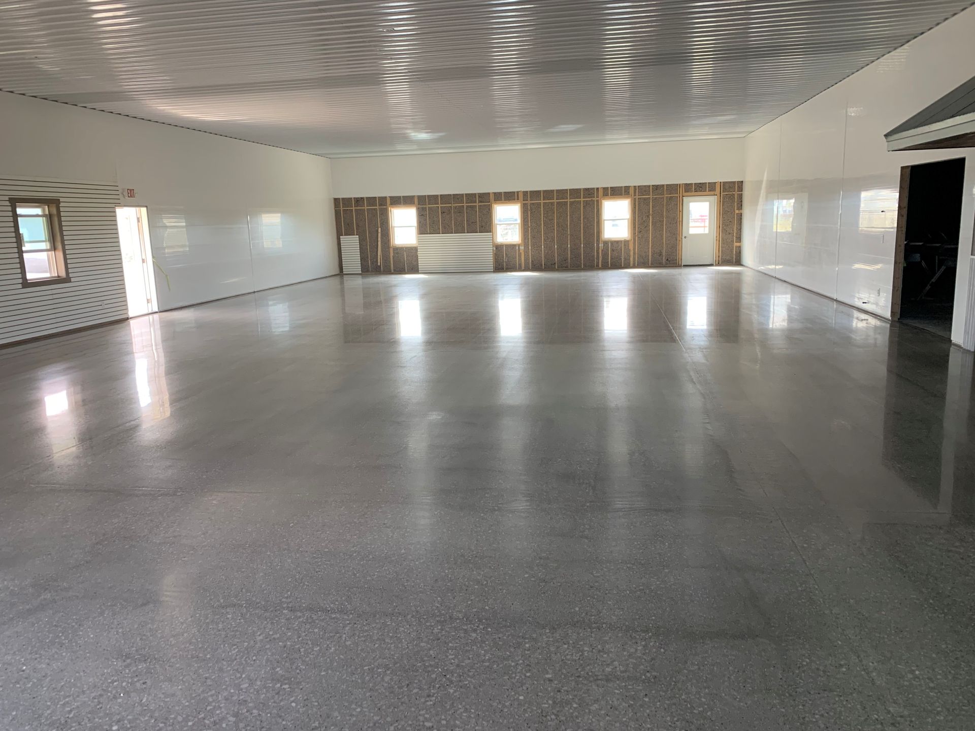 Empty polished hall with a curved patterned ceiling and windows along the far wall.