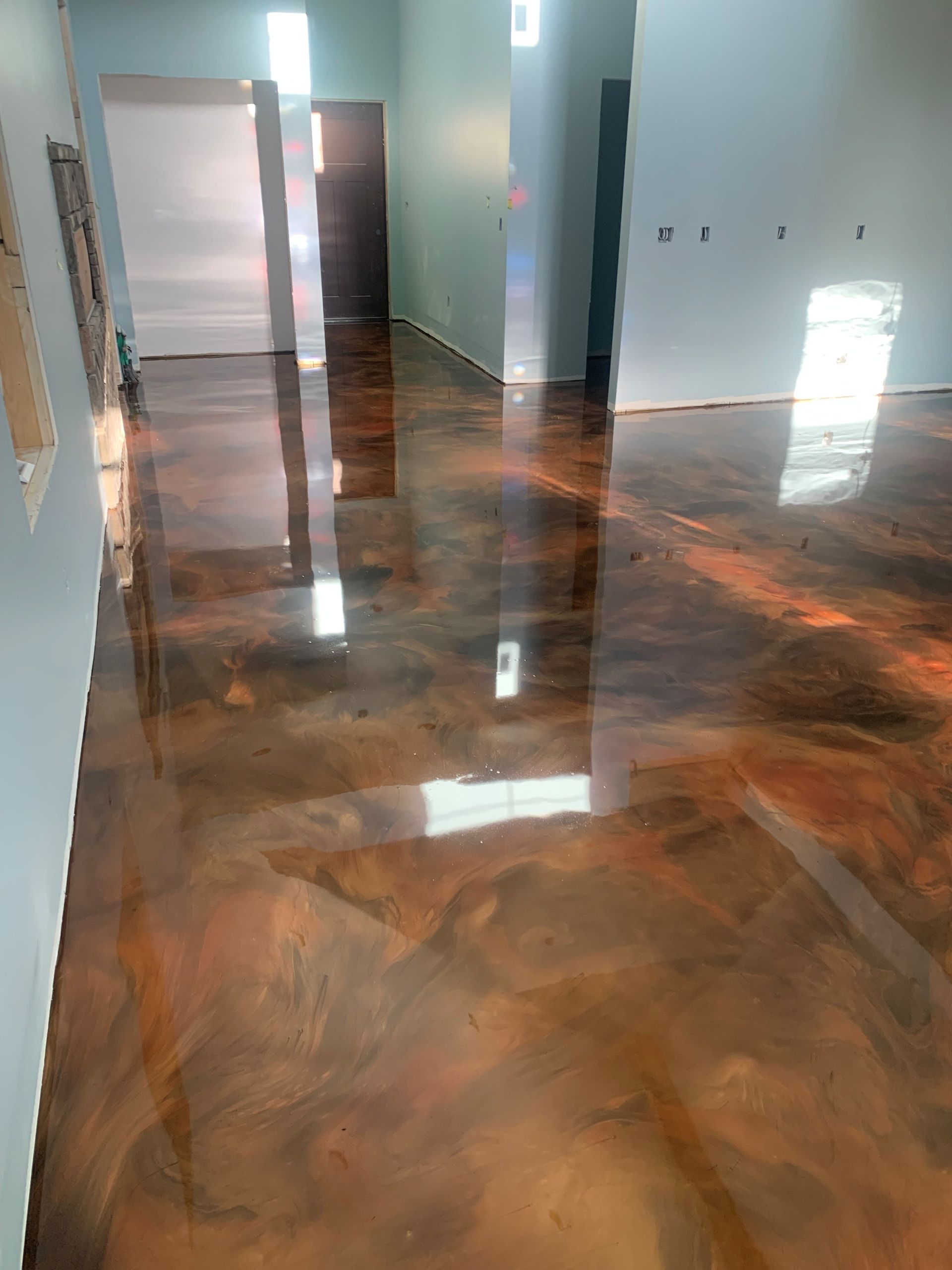 Empty hallway with glossy marbled brown floor and light blue walls, reflecting sunlight from windows.