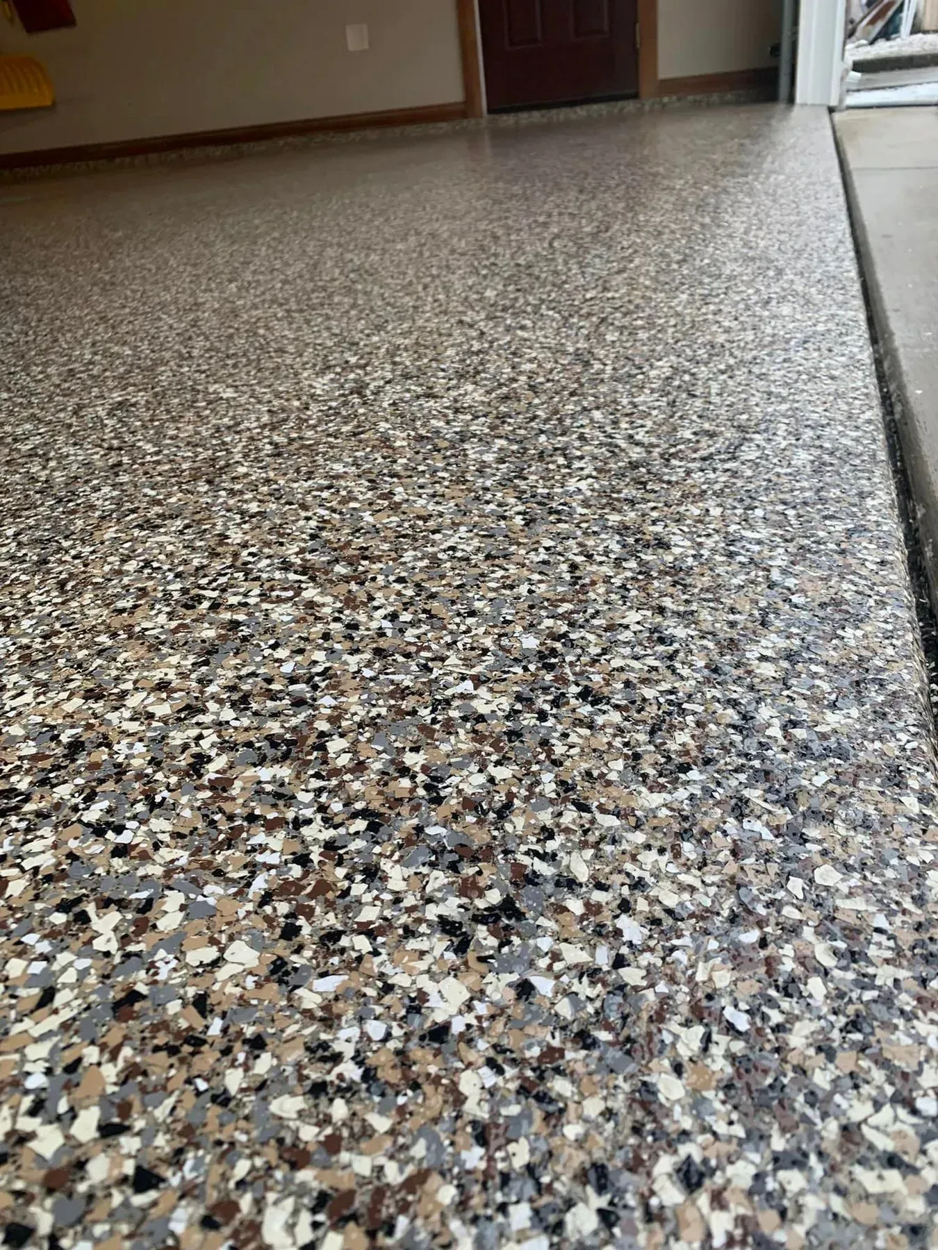 Terrazzo floor extending into a hallway with a door and wall in the background