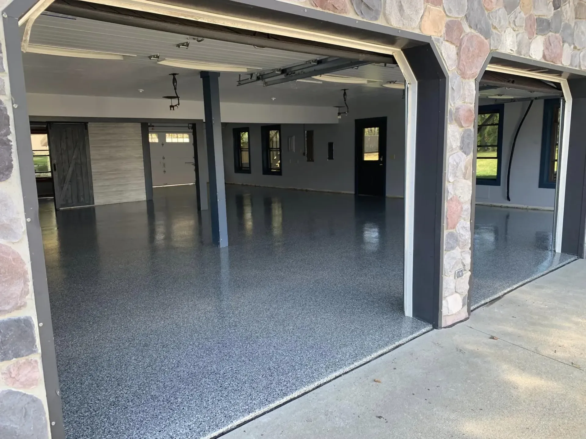 Open garage with glossy speckled epoxy floor and unfinished interior walls.